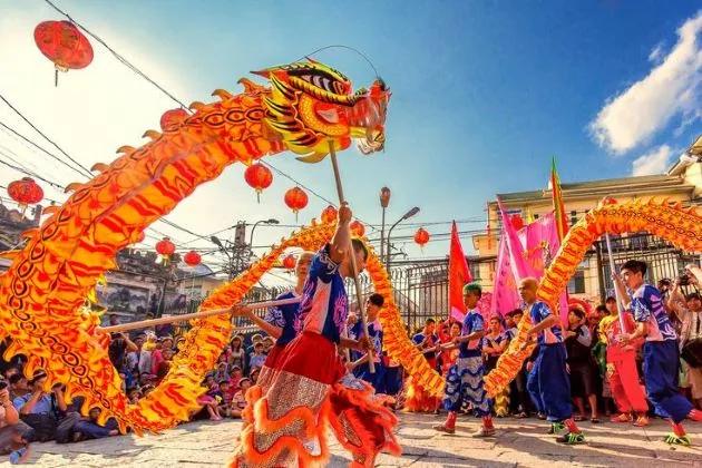Danse du dragon lors d’une fête de rue, costume orange déployé au-dessus de la foule