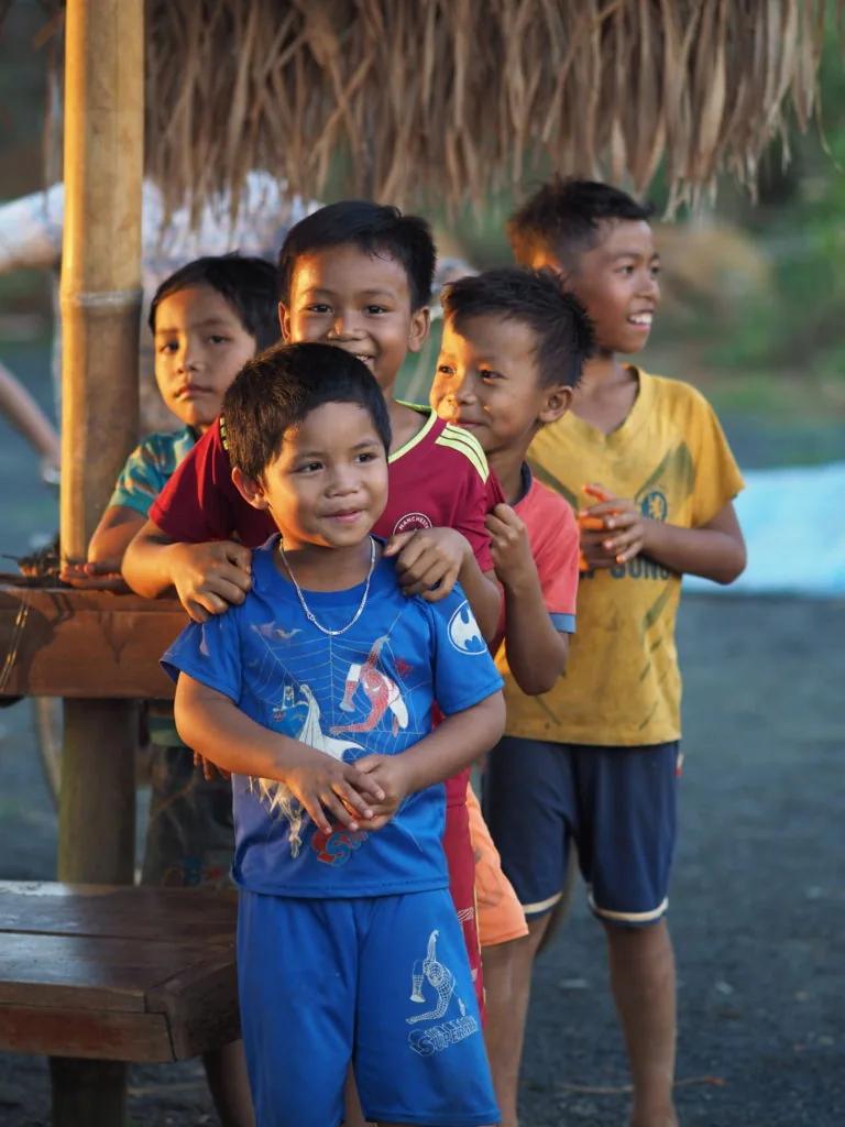 Groupe d’enfants souriants réunis sous un abri de bambou