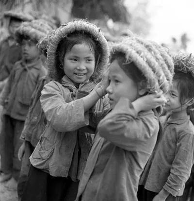 Photographie en noir et blanc : enfants d’une minorité ethnique riant ensemble, coiffés de capuches