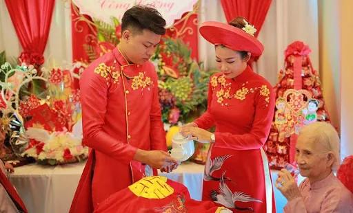 Cérémonie de mariage vietnamienne : les mariés en áo dài rouge devant un autel fleuri