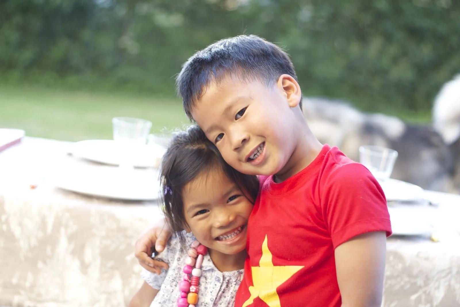 Deux enfants souriants se serrant l’un contre l’autre, l’un portant un tee-shirt aux couleurs du drapeau